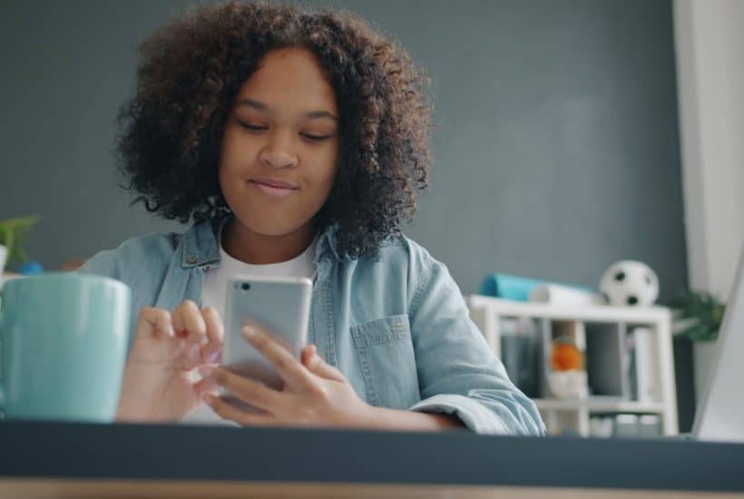 Young girl using a smartphone at a desk.
