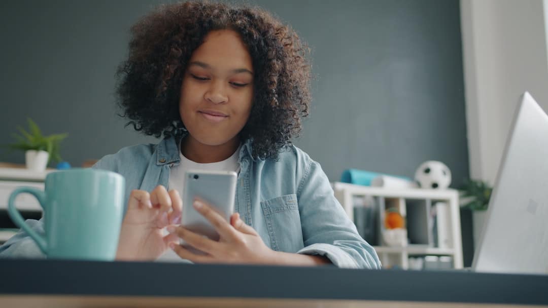 Young girl using a smartphone at a desk.