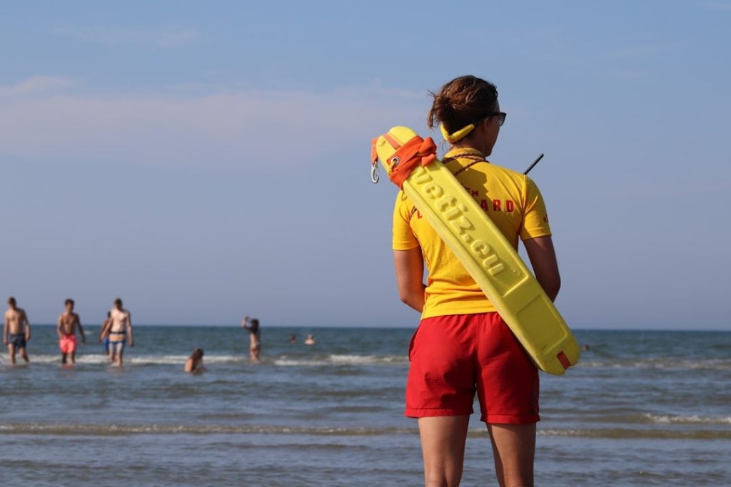 lifeguard by the beach person carrying sport board while standing on shore