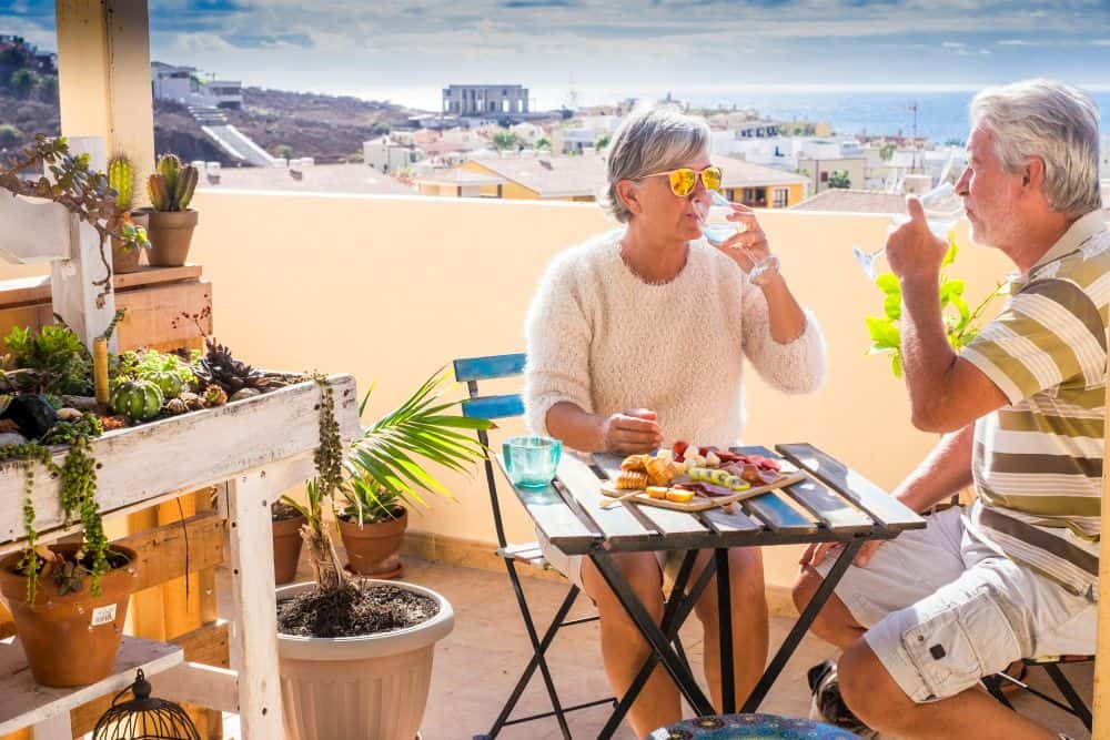 older couple sitting at table with food and drinks enjoying retirement