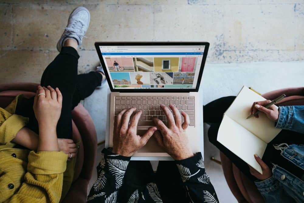 computer with 3 people around it.