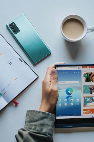 person using Windows 11 computer beside white ceramic mug on white table