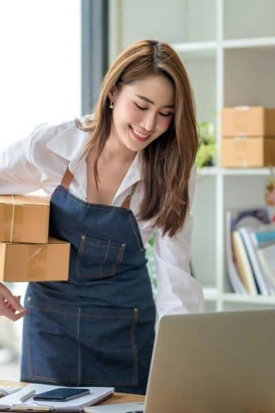 woman looking at laptop and holding packages