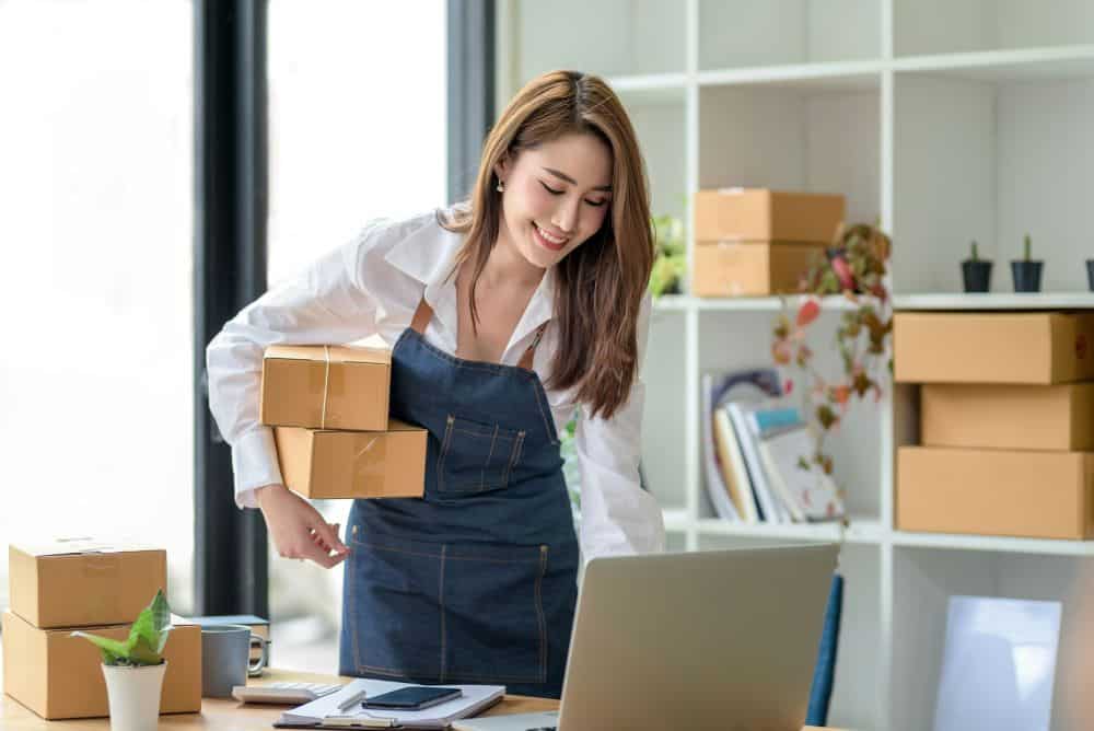 woman looking at laptop and holding packages