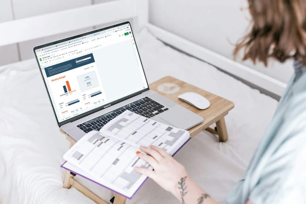 woman at computer with budget on monitor and open planning book