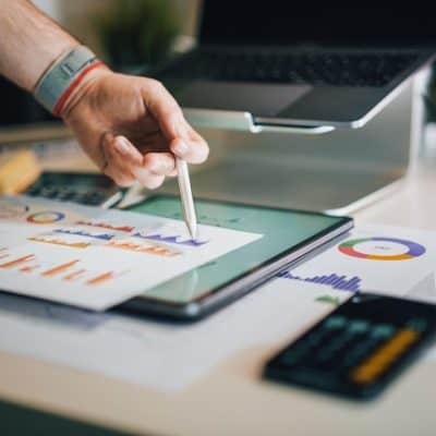 person using stylus on tablet with charts
