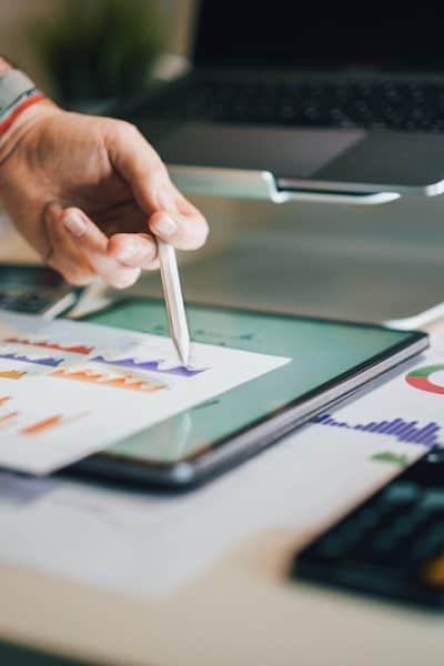 person using stylus on tablet with charts